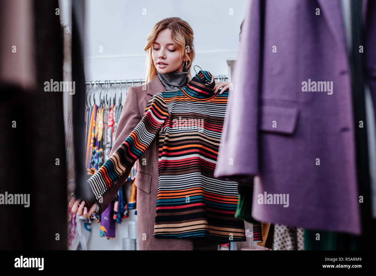 Polo colorati. I giovani alla moda donna attraente shopping e scegliendo a strisce colorate collo polo Foto Stock
