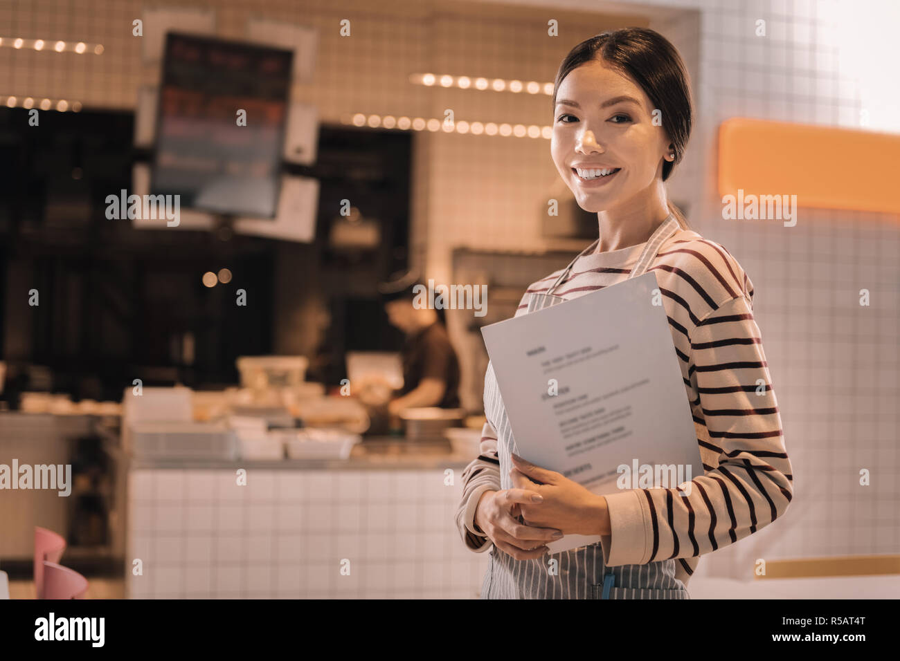 Piacevole bella giovane donna lavora come cameriera in accogliente caffetteria Foto Stock