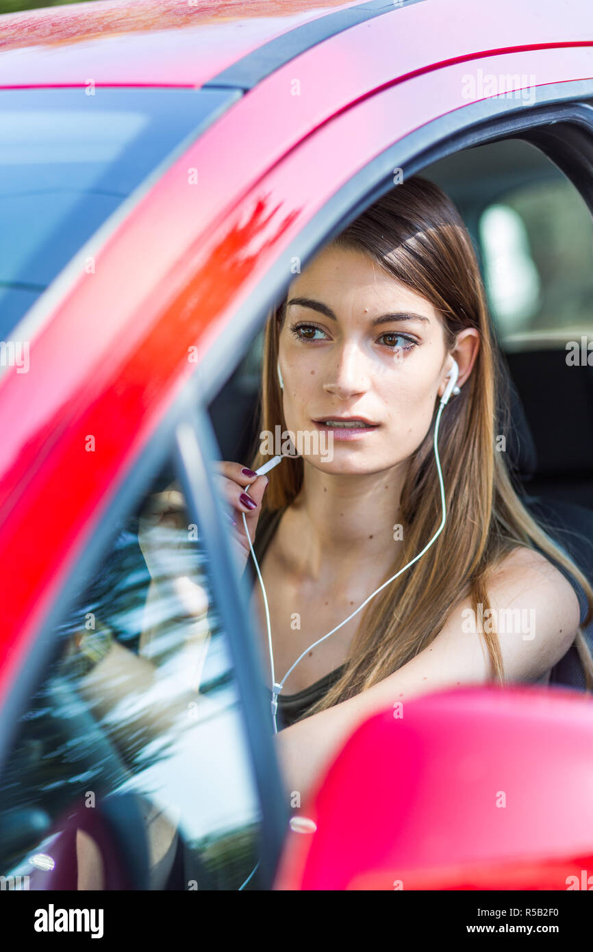 Donna che utilizza un kit vivavoce durante la guida. Foto Stock