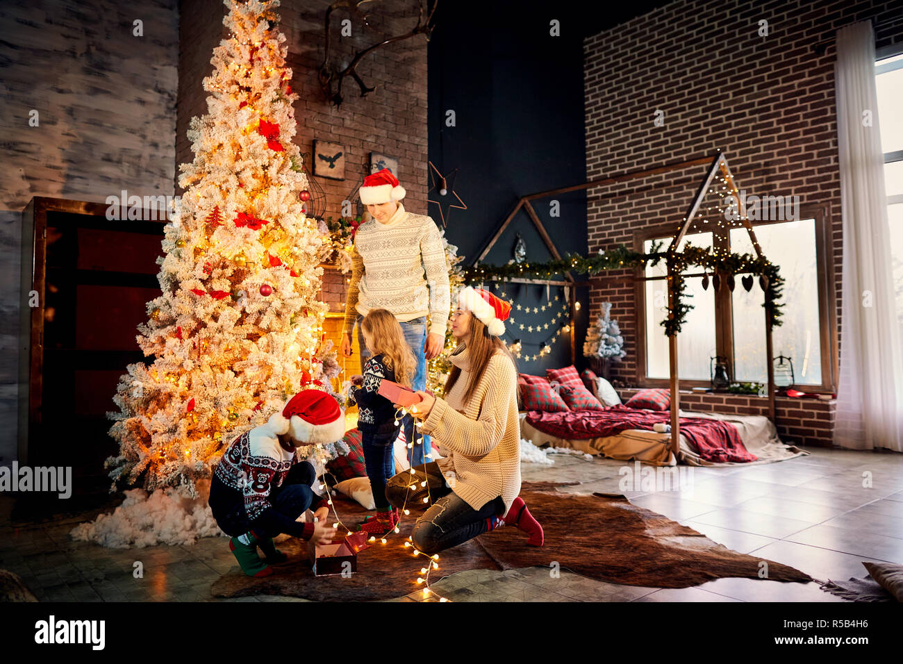 Una famiglia felice decora un albero di Natale a casa. Foto Stock