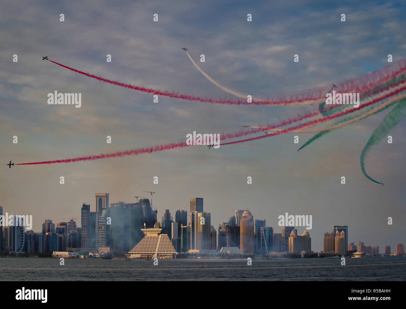 Air Show Doha - italiano Tricolore Frecce dipingere il cielo sopra lo skyline della città con percorsi di colore Foto Stock
