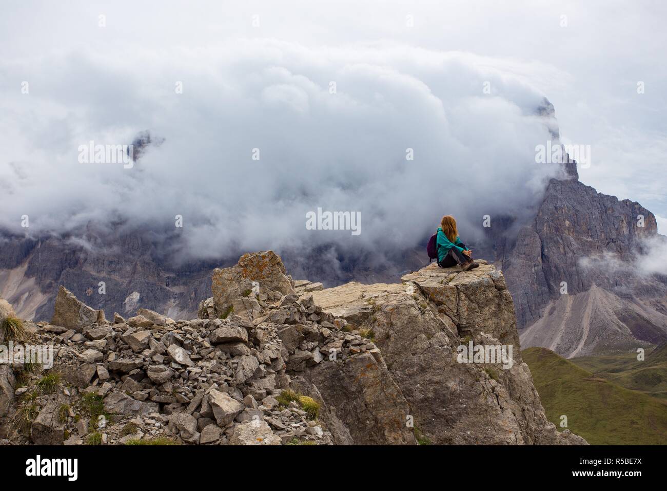 Ragazza escursionista in piedi su una scogliera e guardando le montagne Foto Stock