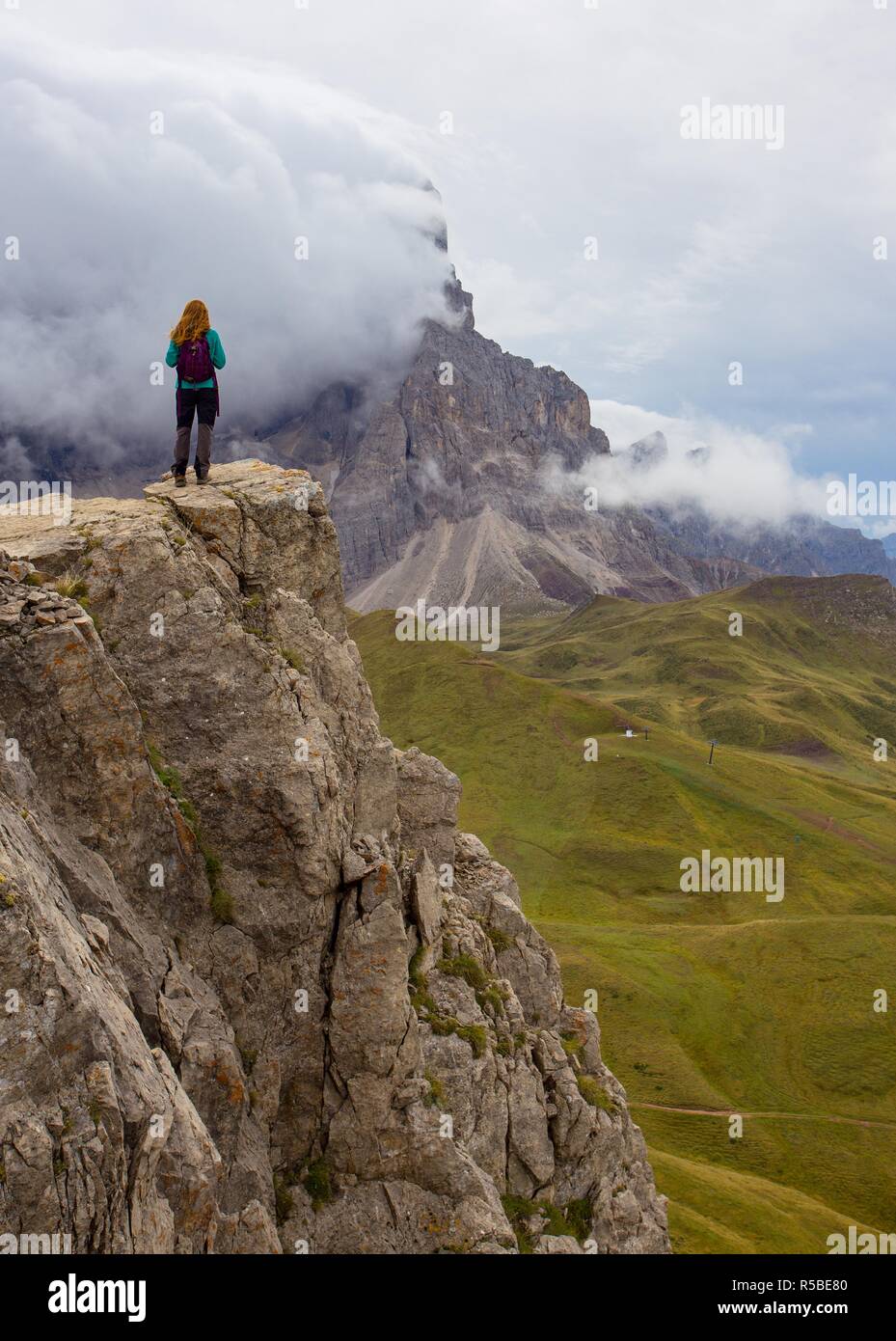 Ragazza escursionista in piedi su una scogliera e guardando le montagne Foto Stock