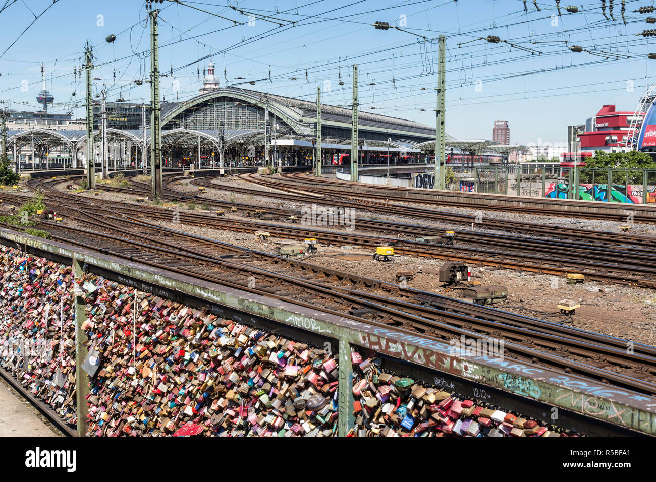 Colonia, Germania. Amore si blocca sulla ringhiera del ponte di Hohenzollern sul Reno. Stazione ferroviaria in background. Foto Stock