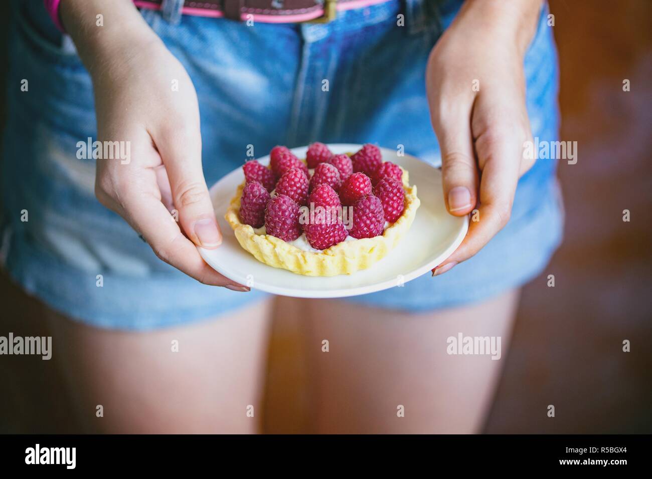 La ragazza tiene nelle sue mani deliziose, utile e bella canapes con lampone Foto Stock