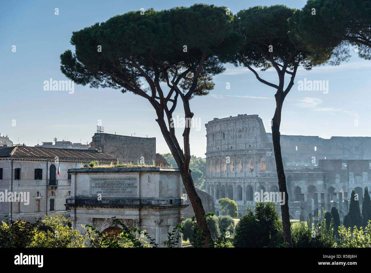 La mattina presto vista attraverso il foro romano verso l'Arco di Tito , con il Colosseo in background, Roma, Italia. Foto Stock