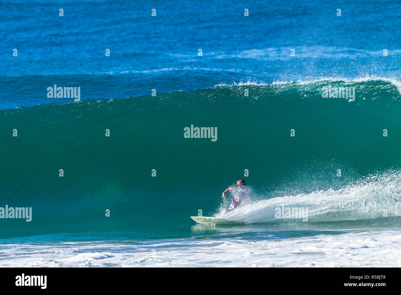 Surfer surf onde oceaniche facendo un fondo forte azione svolta con uno spruzzo di acqua scia dietro. Foto Stock