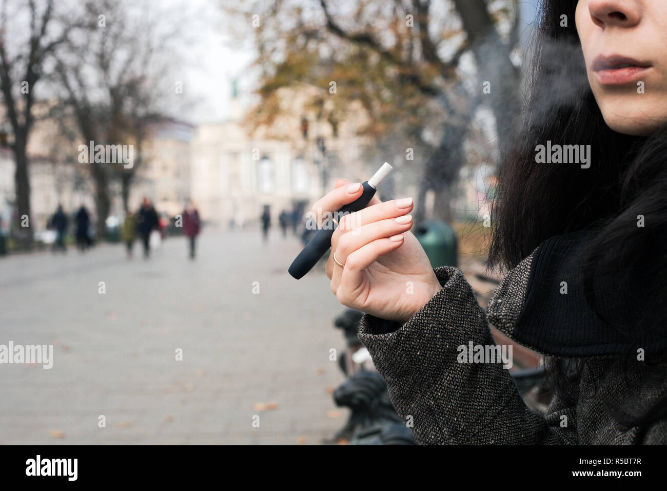 Ragazza di fumare sigaretta elettronica. Brunette donna holding Iqos Foto  stock