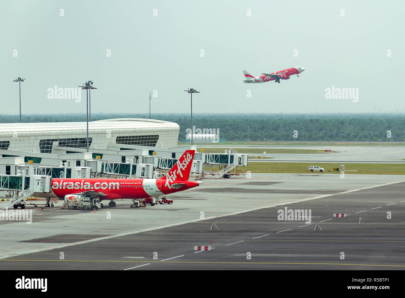 Malaysia, KLIA-2, 04-03-2018: due aeromobili in aeroporto - un piano sta nel parcheggio, l'altro aereo decolla, vista laterale Foto Stock