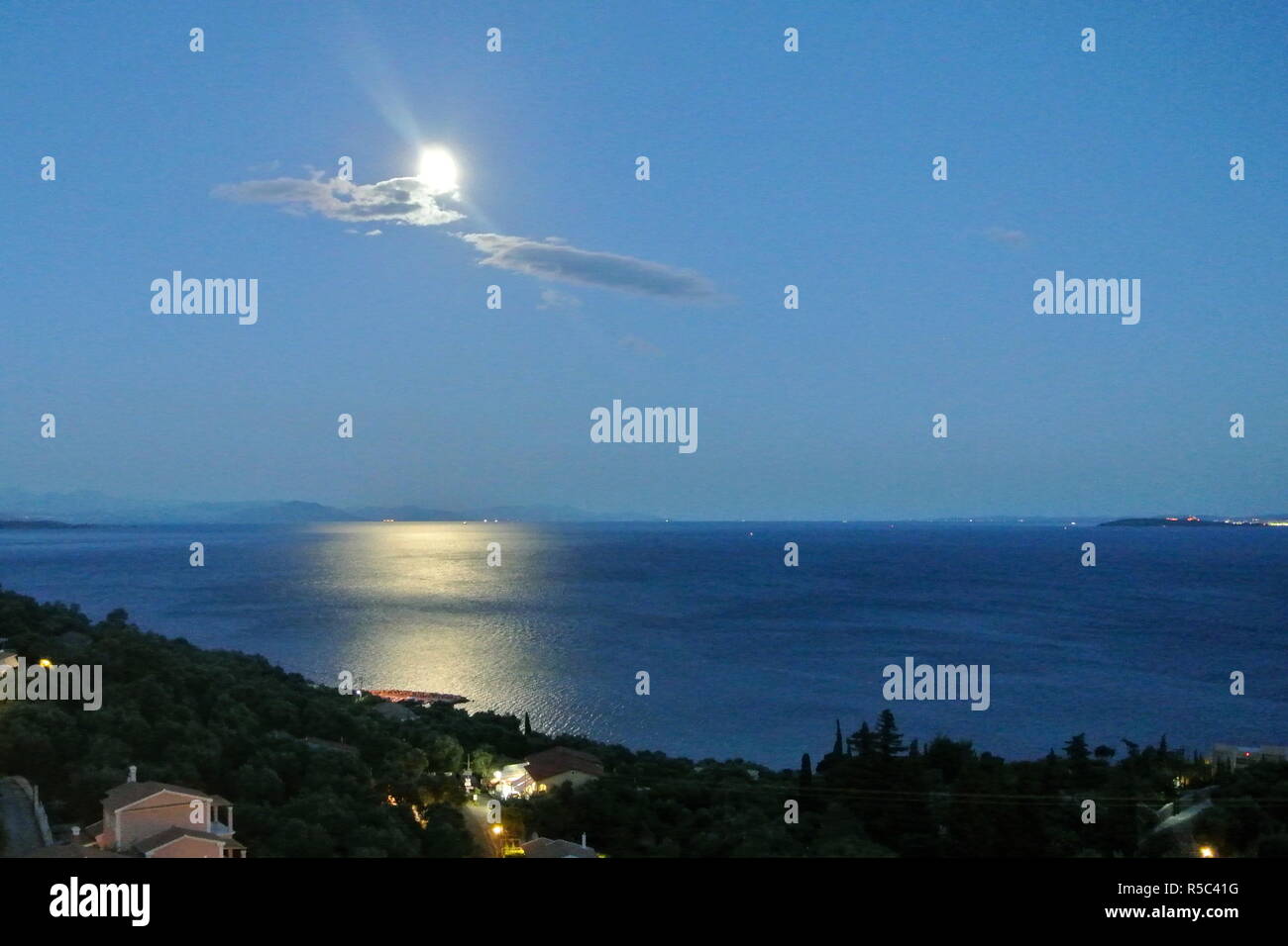 Notte, vista sul Mar Ionio sulla terraferma della Grecia, dalla bellissima isola greca di Corfù. La luce di luna si rifletteva sulle acque ferme. Foto Stock