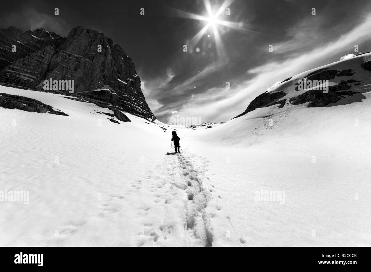 Silhouette di un escursionista in montagna innevata, roccia e cielo con sole e raggi solari. La Turchia, centrale sui monti Taurus, Aladaglar (Anti-Taurus), plateau Edigel Foto Stock