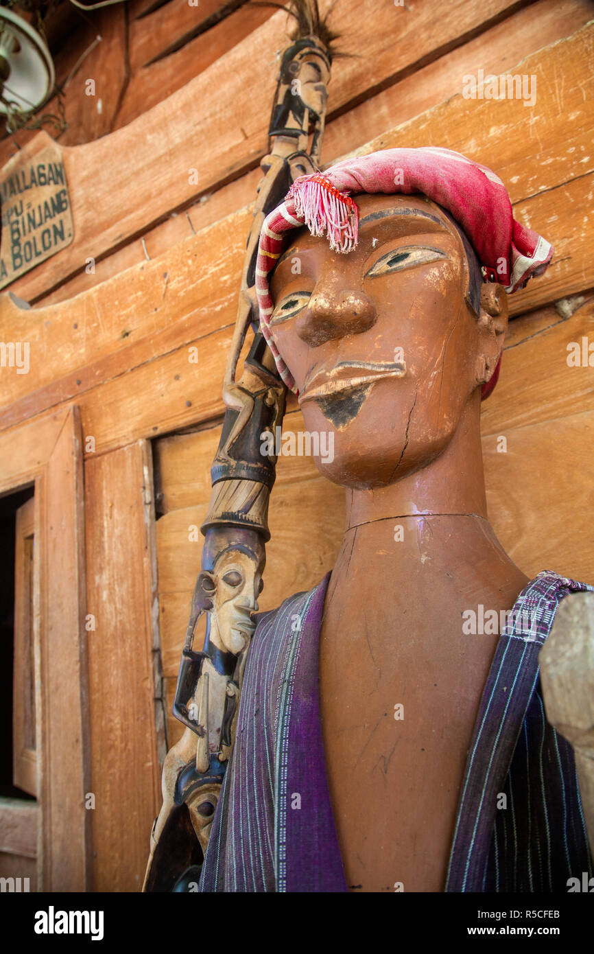 Indonesia, Sumatra, isola di Samosir, Lago Toba, Ambarita, Siallagan village, antichi tradizionali Batak casa in legno, Lifesize immagine del capo azienda uno staff scolpiti con i capi del passato. Foto Stock