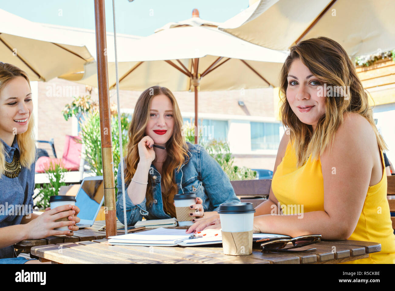 Tre giovani donne millenario sedersi a un coffee shop per un incontro di lavoro Foto Stock