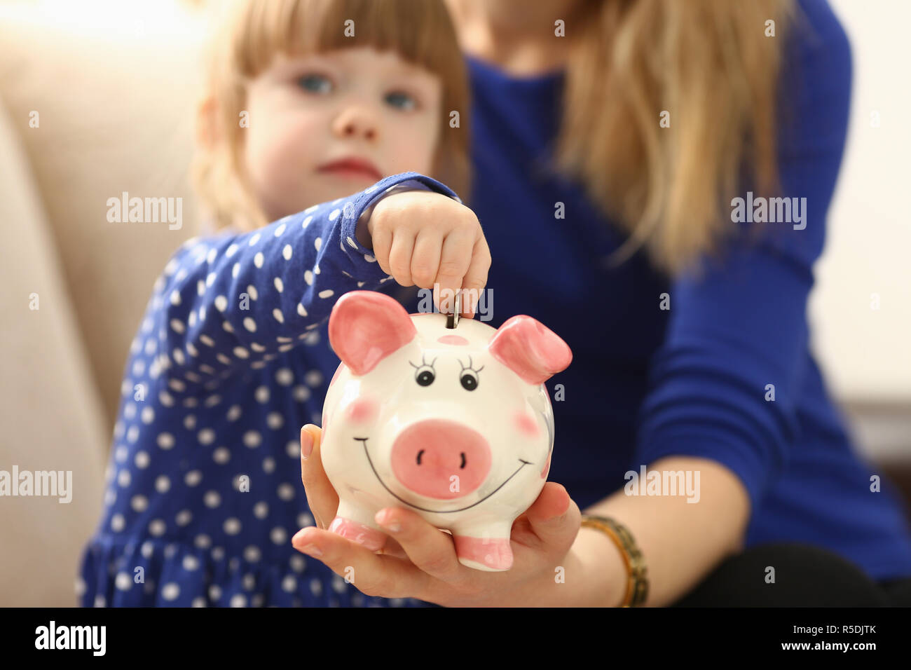 Bambino bambina mettendo a braccio di monete in piggybank Foto Stock