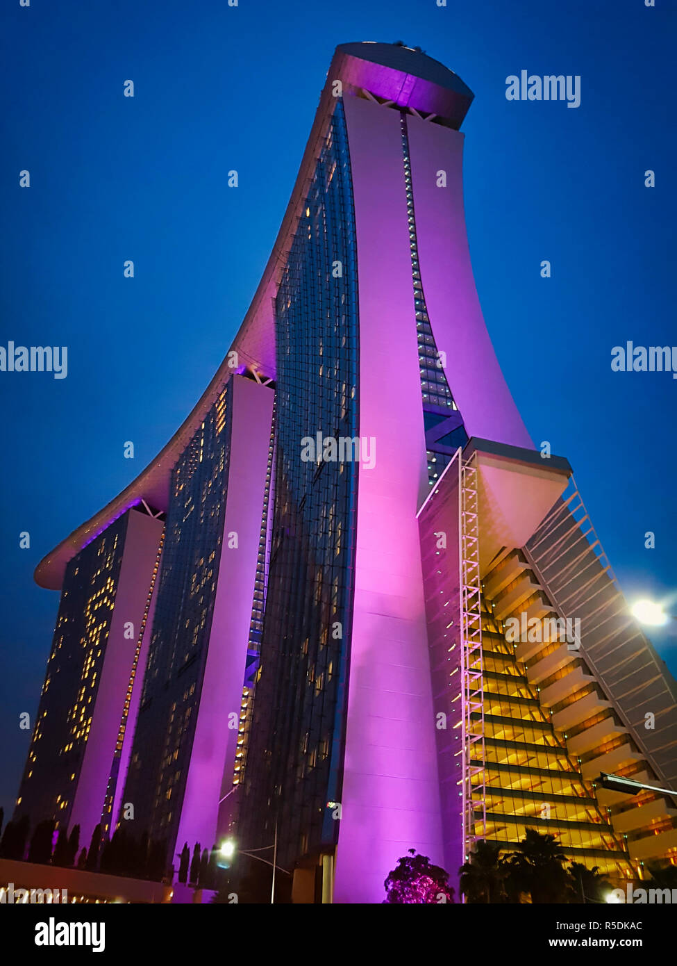 Il Marina Bay Sands edificio di notte in una illuminazione viola contro il blu scuro cielo notturno Foto Stock