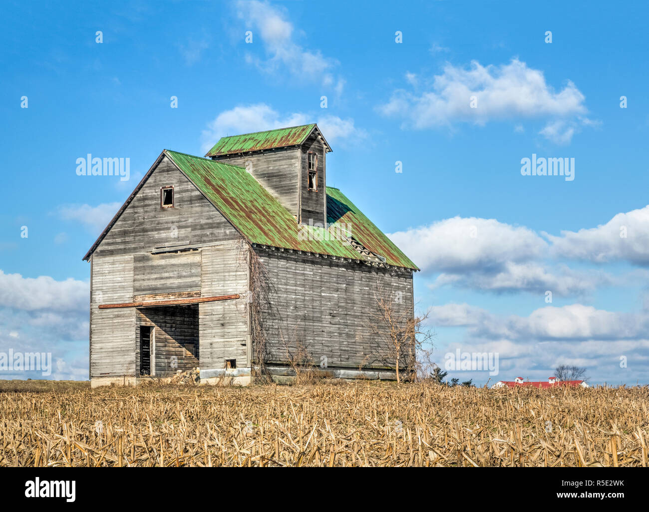 Un rustico vecchio fienile si erge drammaticamente contro un nuvoloso cielo blu in un territorio rurale Ohio cornfield. Foto Stock