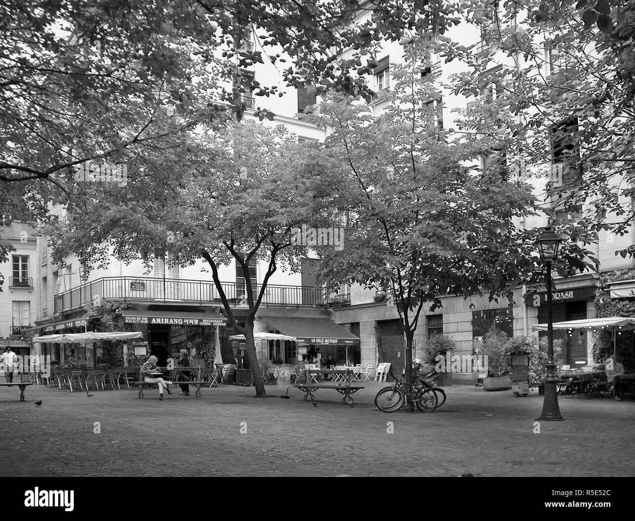Place du Marché-Sainte-Catherine: biciclette, alberi, cafe, passanti in una tranquilla piazzetta, Marais, Paris, Francia. Versione in bianco e nero Foto Stock