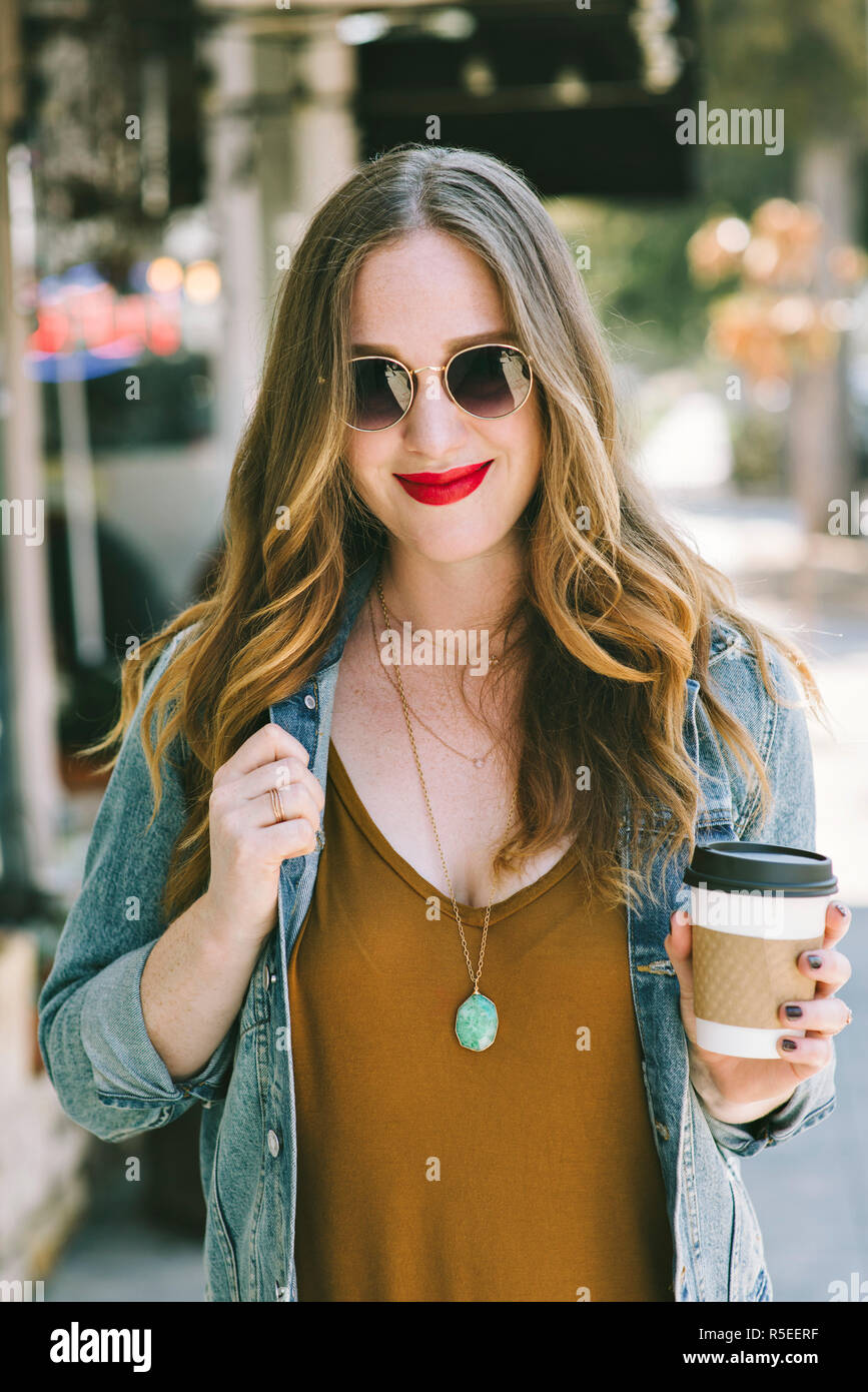 Una donna giovane e alla moda e la millenaria indossa gli occhiali da sole e beve caffè Foto Stock