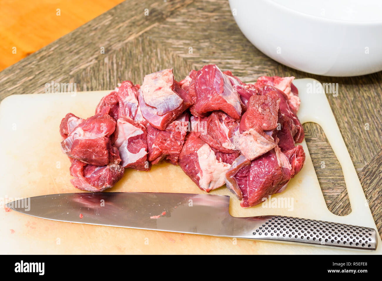 Pila di tagliare la carne cruda (chuck parte) e il coltello sul tagliere. Foto Stock