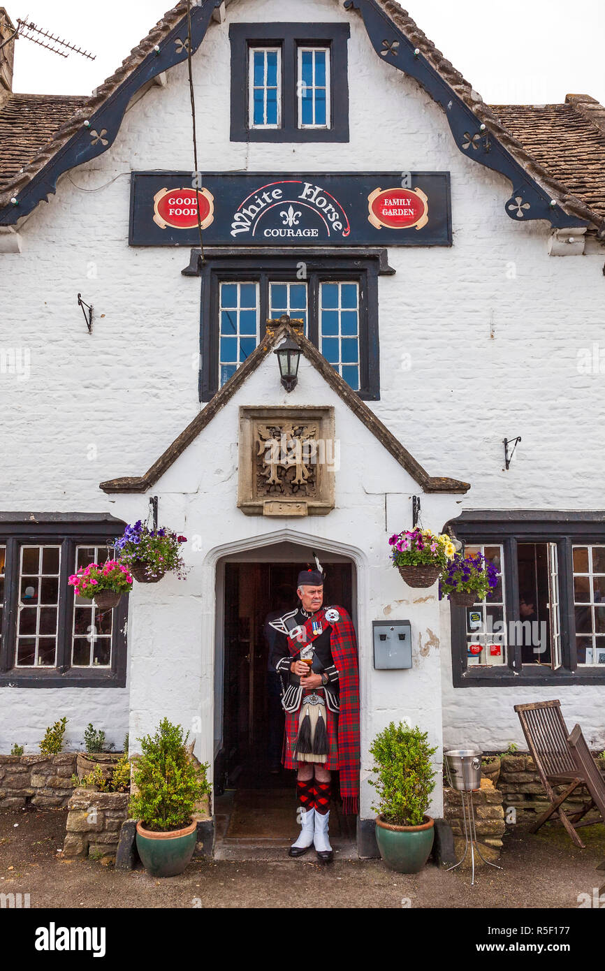 Gli scozzesi piper si fermò in pub porta, Biddestone, Wiltshire, Regno Unito Foto Stock