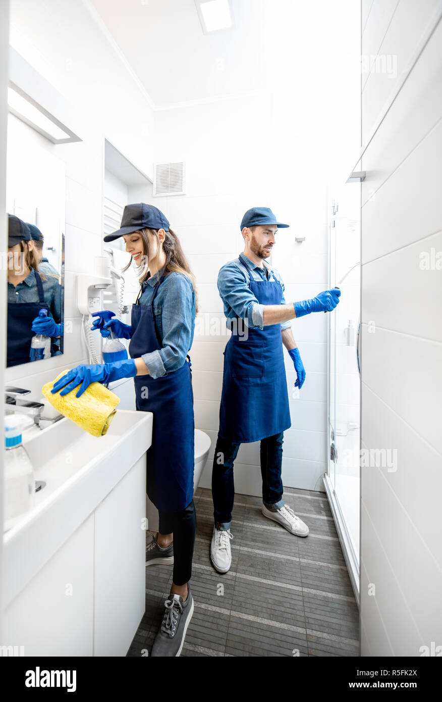 Giovane come pulitori professionali in uniforme blu bagno di pulizia. Il servizio di pulizia concept Foto Stock