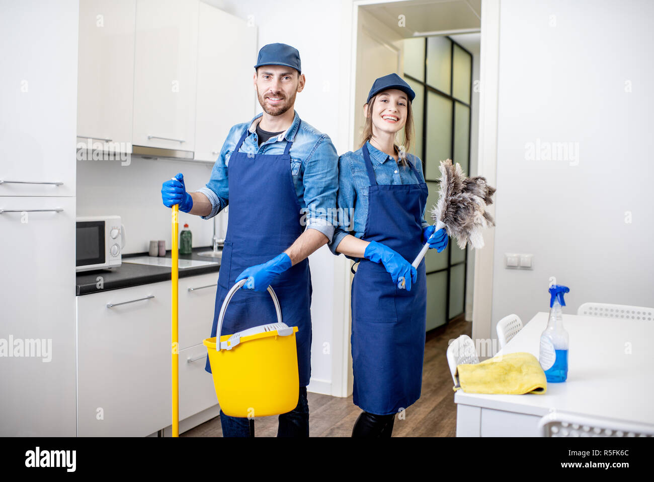 Ritratto di un giovane come pulitori professionali in uniforme in piedi  insieme con attrezzi per la pulizia in ambienti interni Foto stock - Alamy