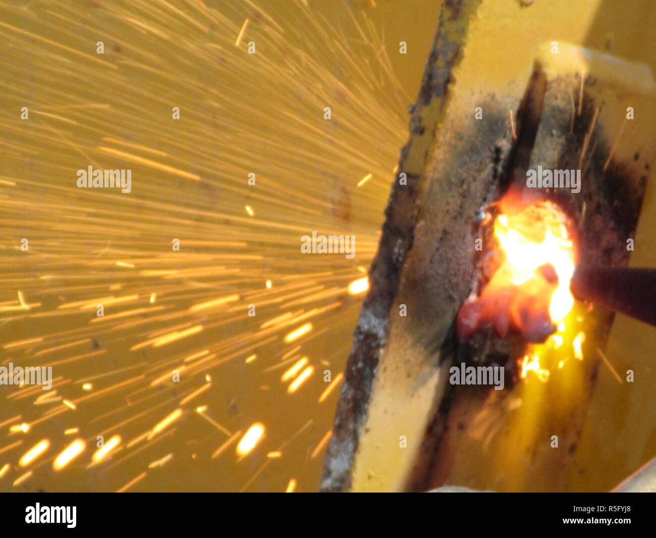 Le scintille di fuoco da acciaio macchine di taglio quando gli uomini stanno utilizzando la smerigliatrice a disco per il taglio di acciaio o l'ossigeno da saldatura a saldatura di parti in acciaio insieme Foto Stock