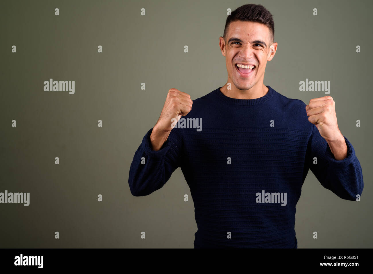 Giovane uomo felice con le braccia sollevate contro sfondo colorato Foto Stock