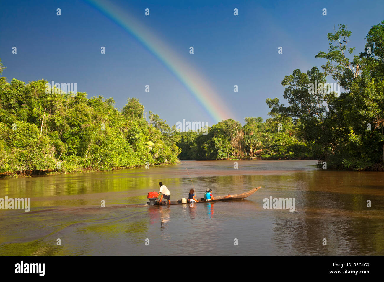 Venezuela, Delta Amacuro, Delta Orinoco, Warao persone in barca sul fiume Nararina con arcobaleno nel cielo in tempesta Foto Stock