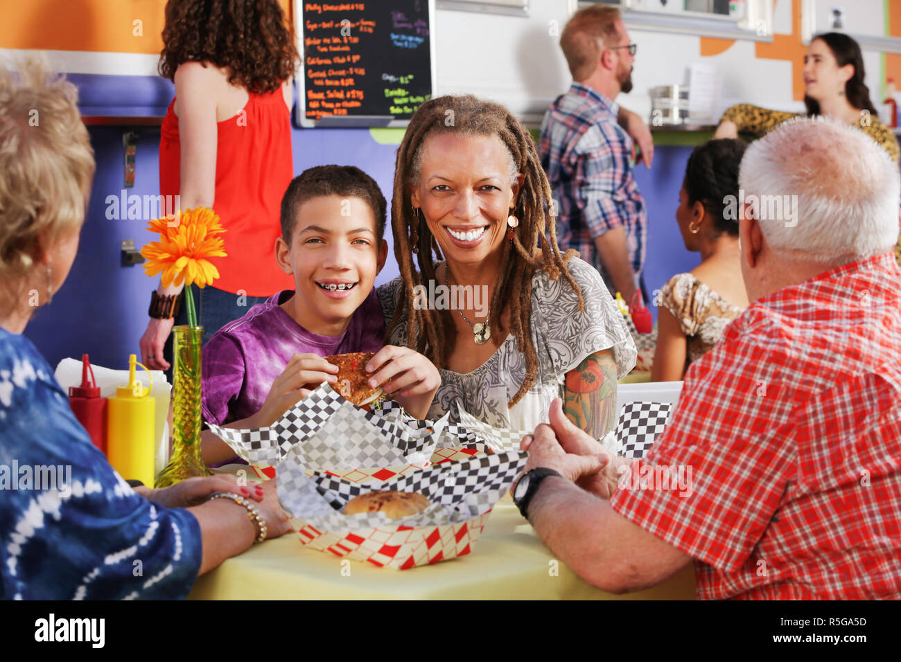 La madre e il suo figlio adolescente a pranzo con gli anziani Foto Stock