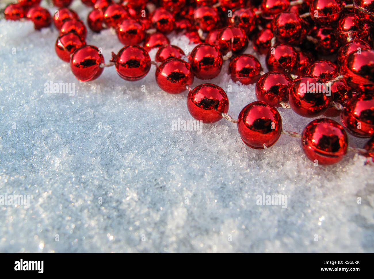 Perle di rosso nell'angolo di uno sfondo di neve fresca in giornata soleggiata. Spazio per copiare, testo le tue parole. Foto Stock