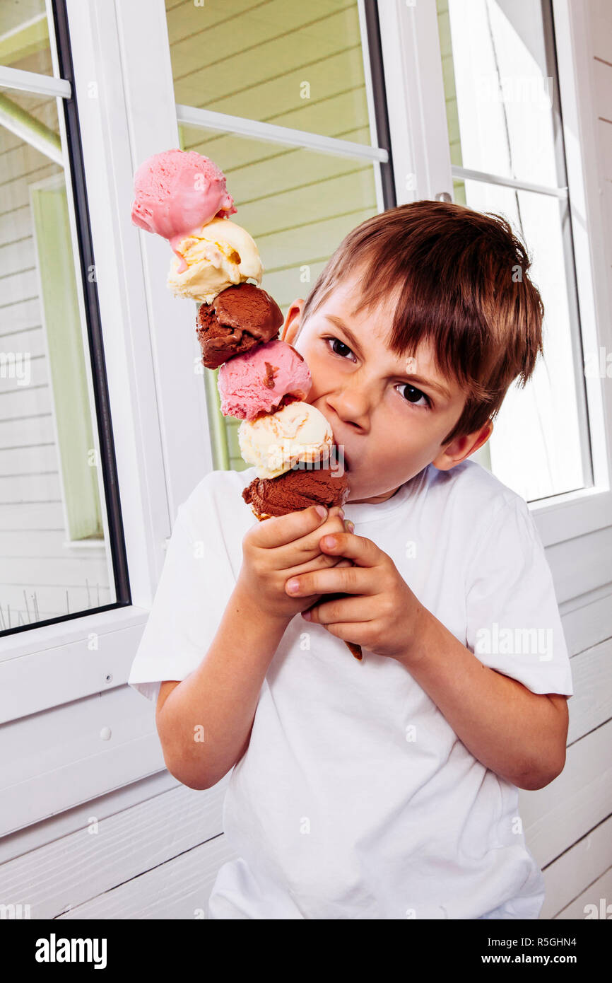 Ragazzo di mangiare un alto cono gelato Foto Stock