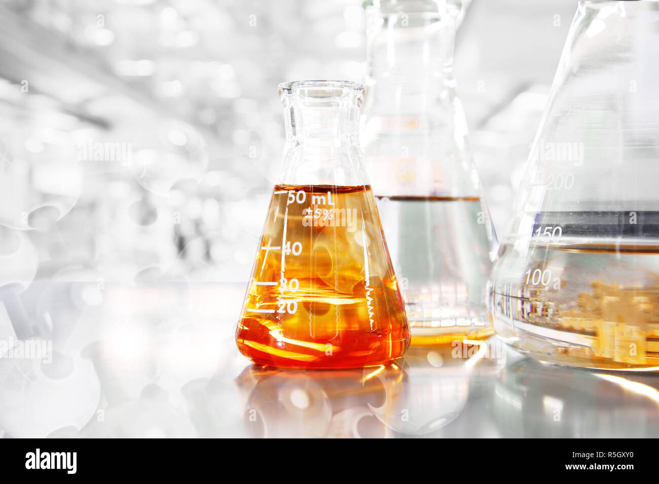 Arancione in modo conico in tre fiasche con struttura chimica di insegnamento delle scienze e lo sfondo di laboratorio Foto Stock