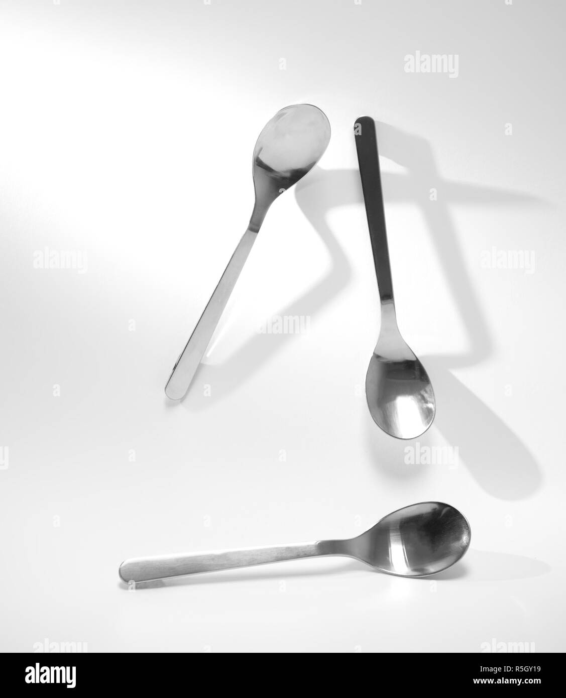 Tre metallo argento cucchiaino per mangiare con forte ombra nera su sfondo bianco Foto Stock