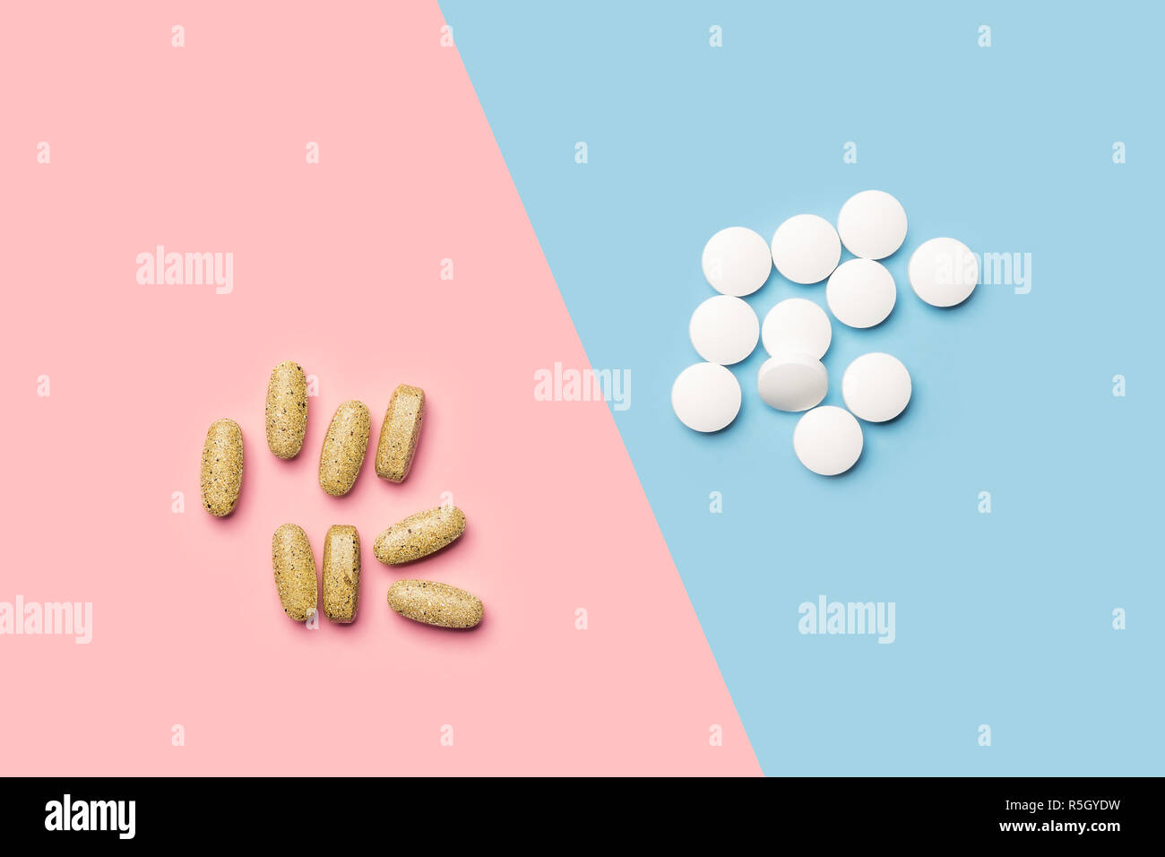 Un mucchio di pillole di bianco e un mucchio di vitamine giallo su blu luminoso e sfondo rosa shot con studio luce da sopra Foto Stock