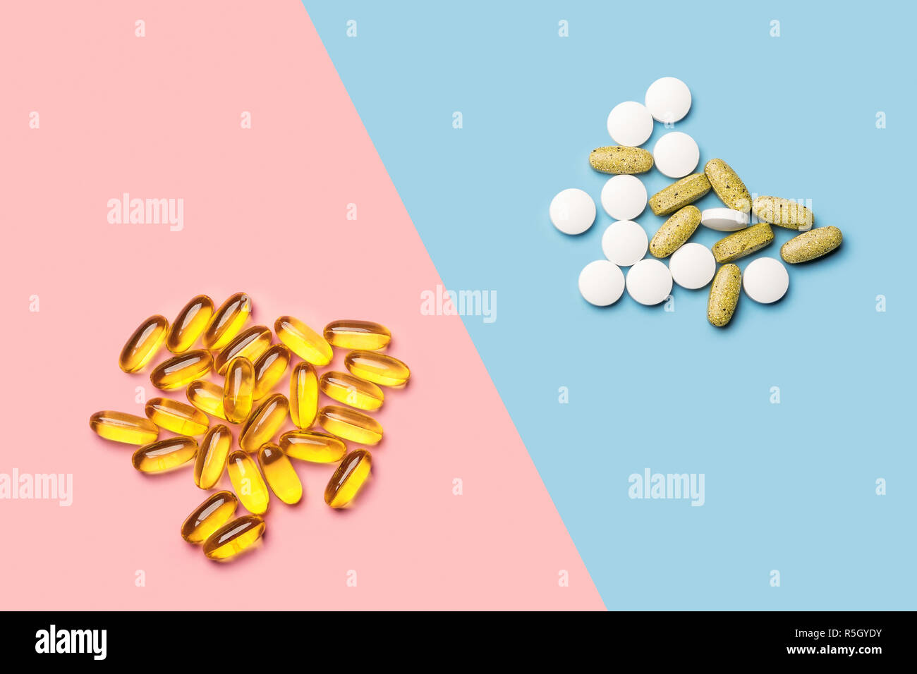 Un mucchio di pillole di bianco e giallo di vitamine e di una pila di giallo olio di pesce capsule su un blu brillante e sfondo rosa shot con studio luce da sopra Foto Stock