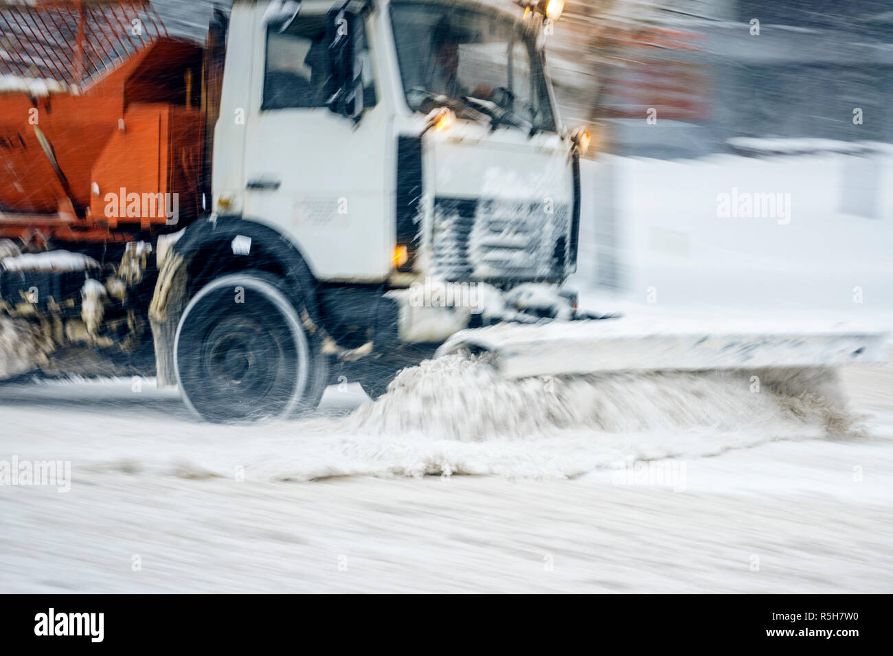 Snow Plough carrello rimuove la neve dal city road. Tempesta di neve in città - stagionale abstract motion blur sullo sfondo Foto Stock