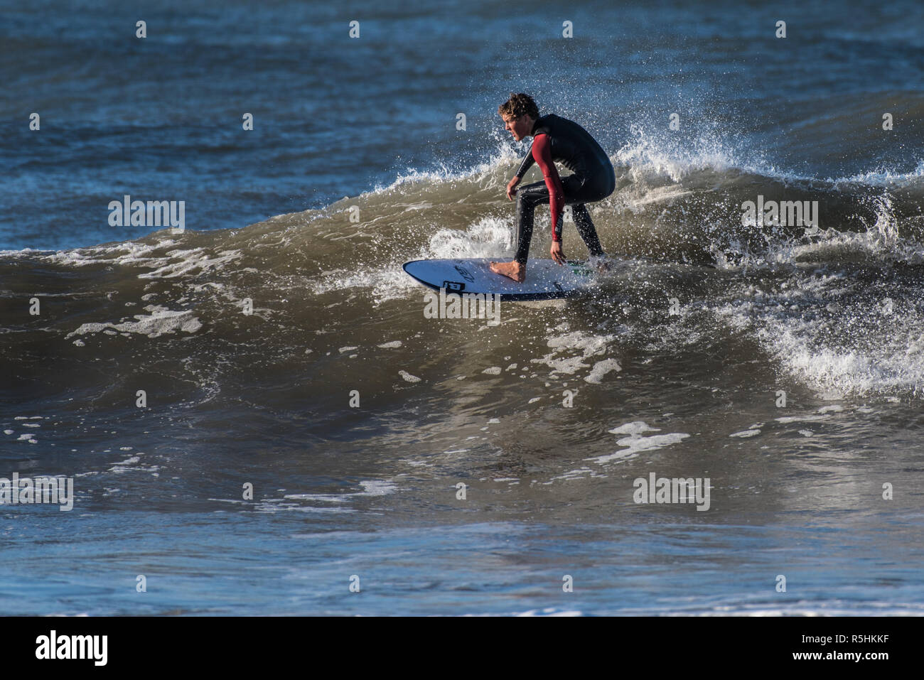 Giovane maschio surfer tenendo alta la linea vicino a labbro onde navigando restanti northwest rigonfiarsi di Ventura, California, Stati Uniti d'America il 1 dicembre 2018. Foto Stock