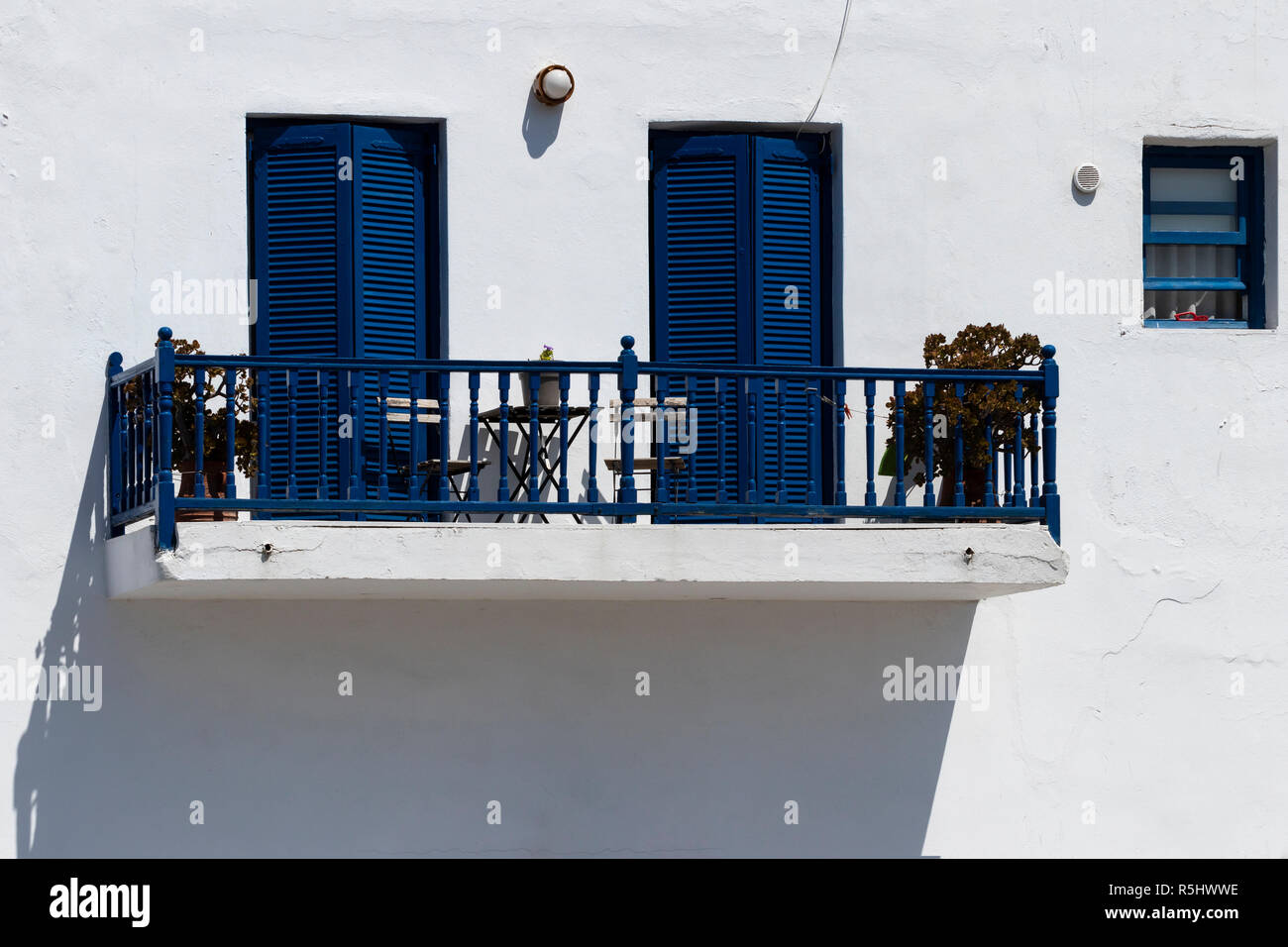 Il balcone di una tradizionale casa greca con finestre blu e pareti dipinte di bianco Foto Stock