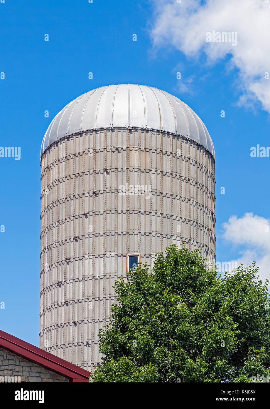 Un silo torre sorge contro un nuvoloso cielo blu su una fattoria del Midwest. Foto Stock