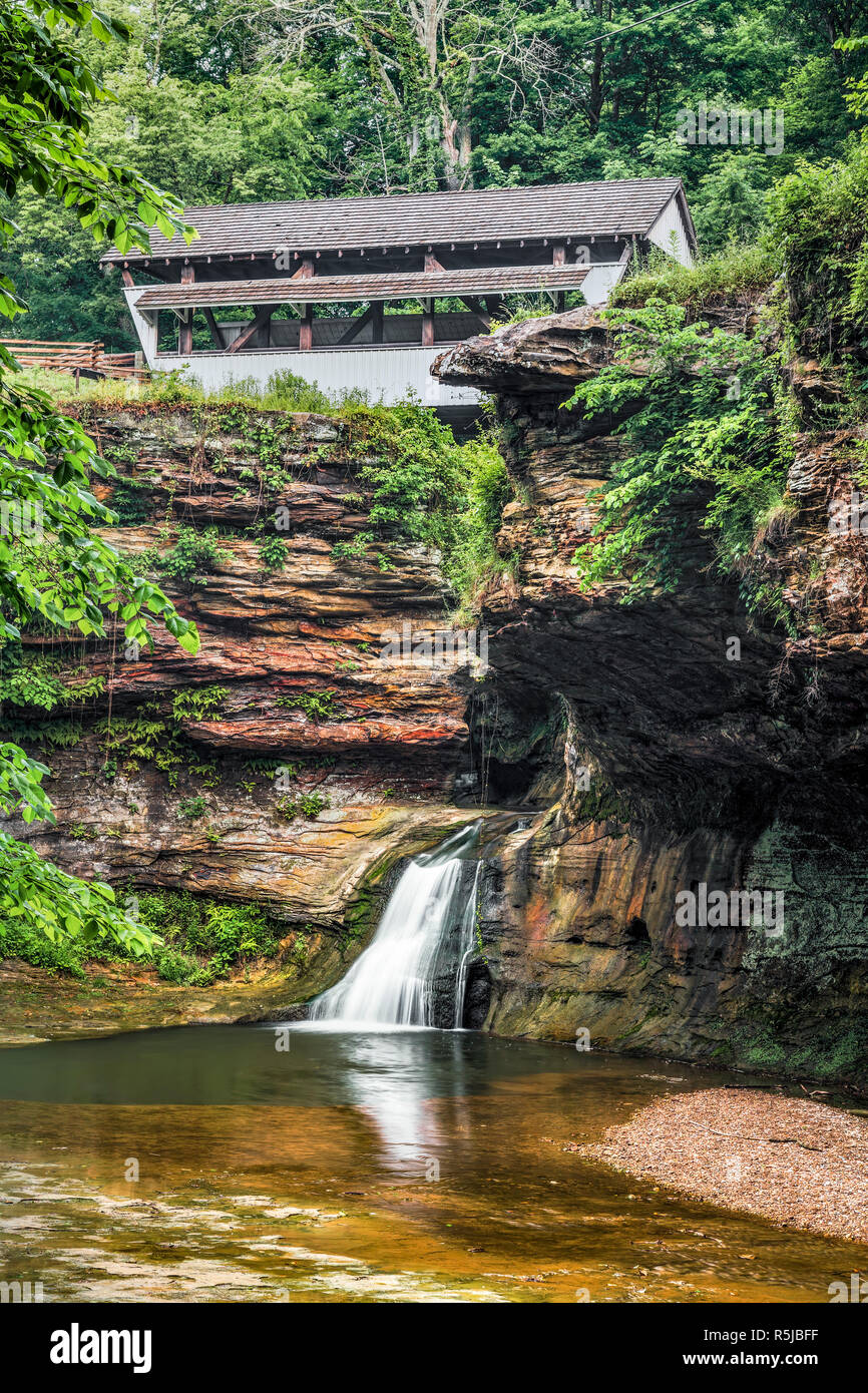 Le sorgenti del fiume Hocking emergono da un anfratto roccioso e splash su una cascata sotto il mulino di roccia ponte coperto nella Contea di Fairfield, Ohio. Foto Stock