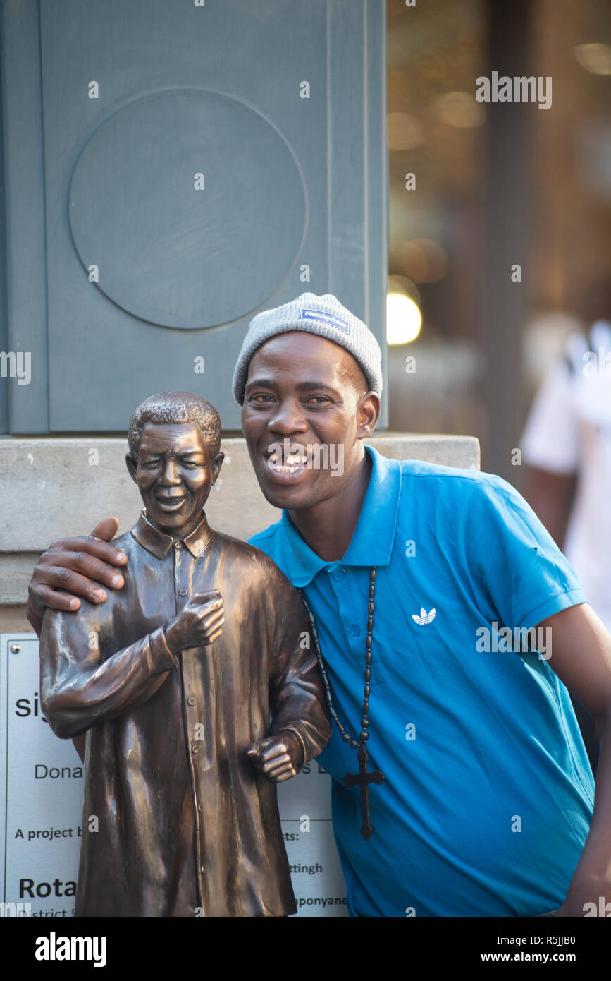 Johannesburg, Sud Africa, 1 dicembre 2018. Un uomo gode di prendere un selfie con una miniatura Nelson Mandela statua, accanto a quella più grande, Nelson Mandela Square di Sandton. Il Sud Africa sta celebrando il centenario di Madiba la nascita. Credito: Eva-Lotta Jansson/Alamy Live News Foto Stock