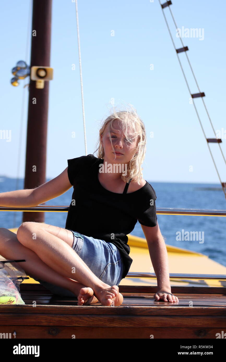 La ragazza si siede sul ponte della nave Foto Stock