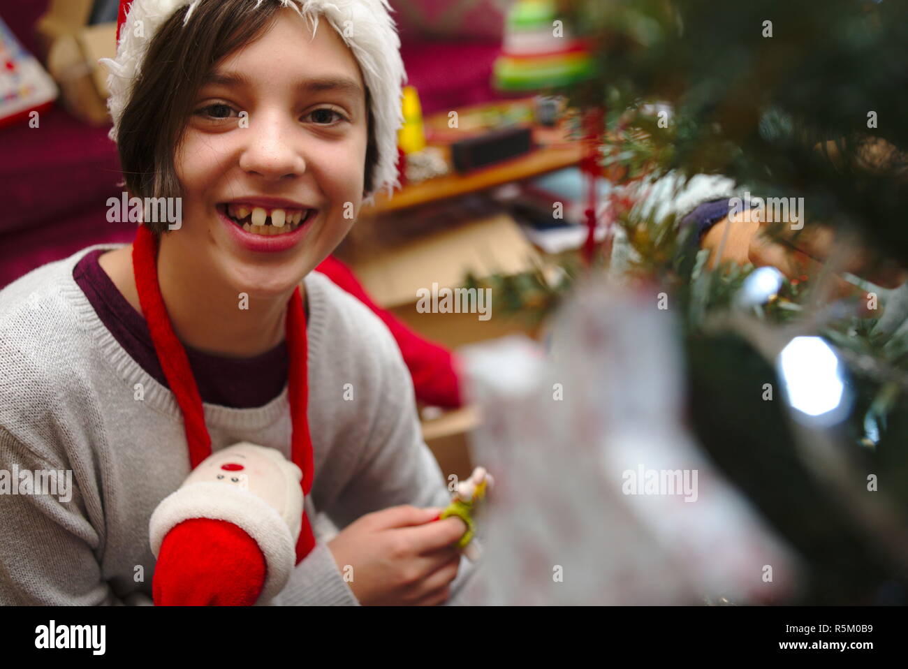 Felice bambino sorridente che decora l'albero di Natale a dicembre. Foto Stock