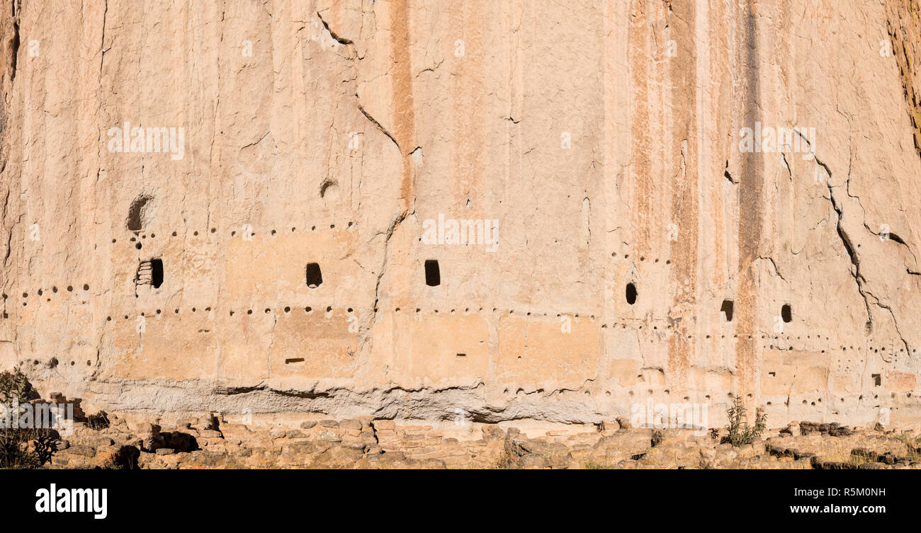 Panorama di abbandono di antiche abitazioni sulla scogliera e grotte in una massiccia scogliera con adobe rovine presso la Casa lunga in Bandelier National Monument Foto Stock