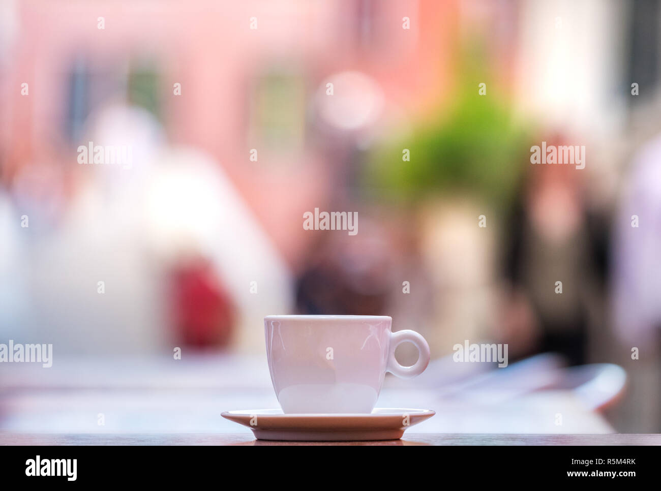 Una tazza di caffè espresso su di un tavolo di legno aperto con persone in background. Foto Stock