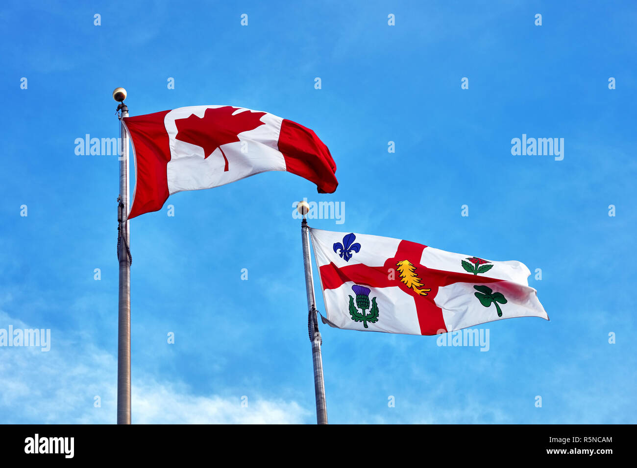 Bandiera canadese e il flag di Montreal sventola sul cielo azzurro sfondo Foto Stock