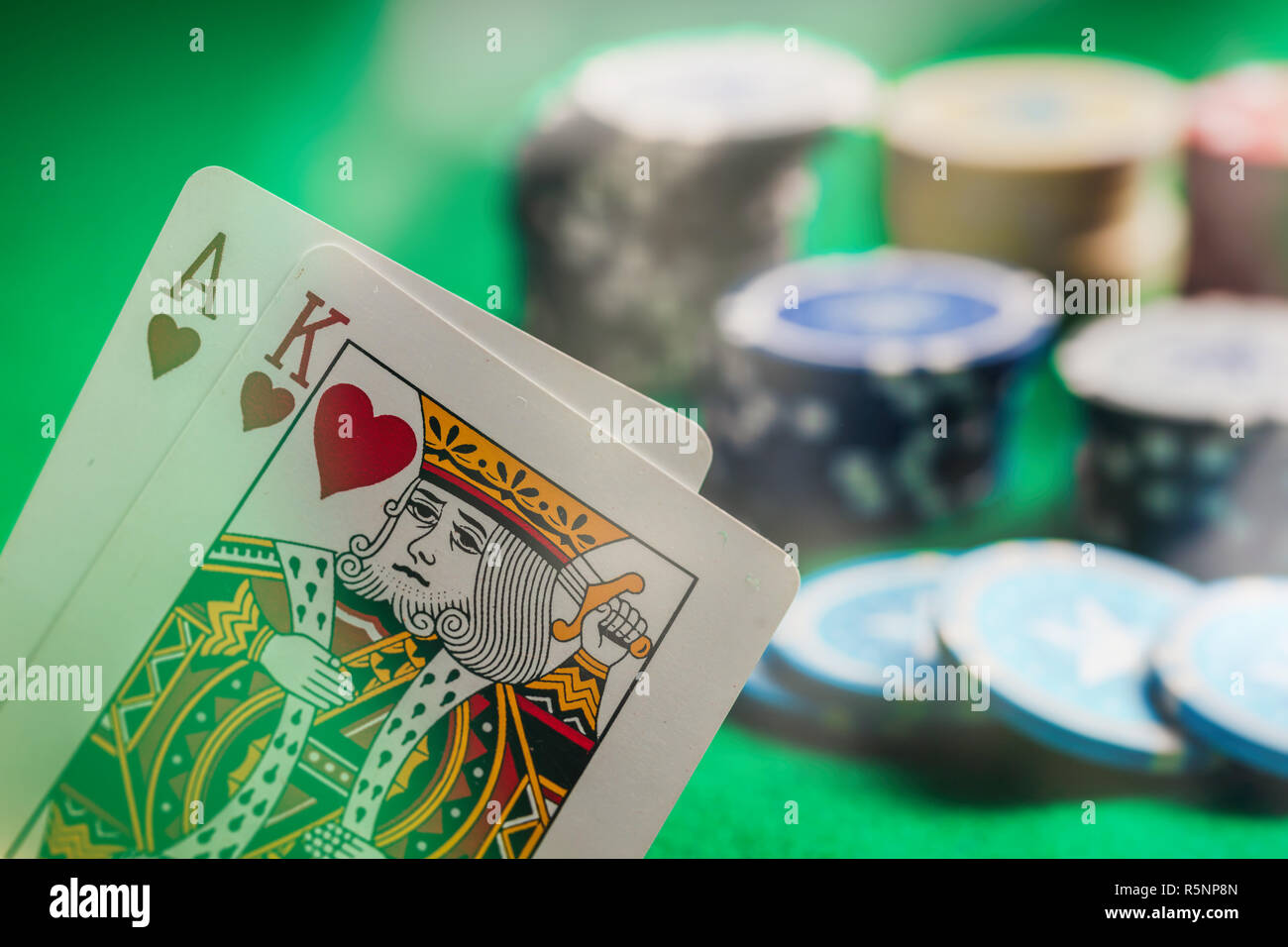 Casinò, il concetto di gioco d'azzardo. Asso e Re di Cuori e poker chips sul feltro verde sfondo astratto Foto Stock