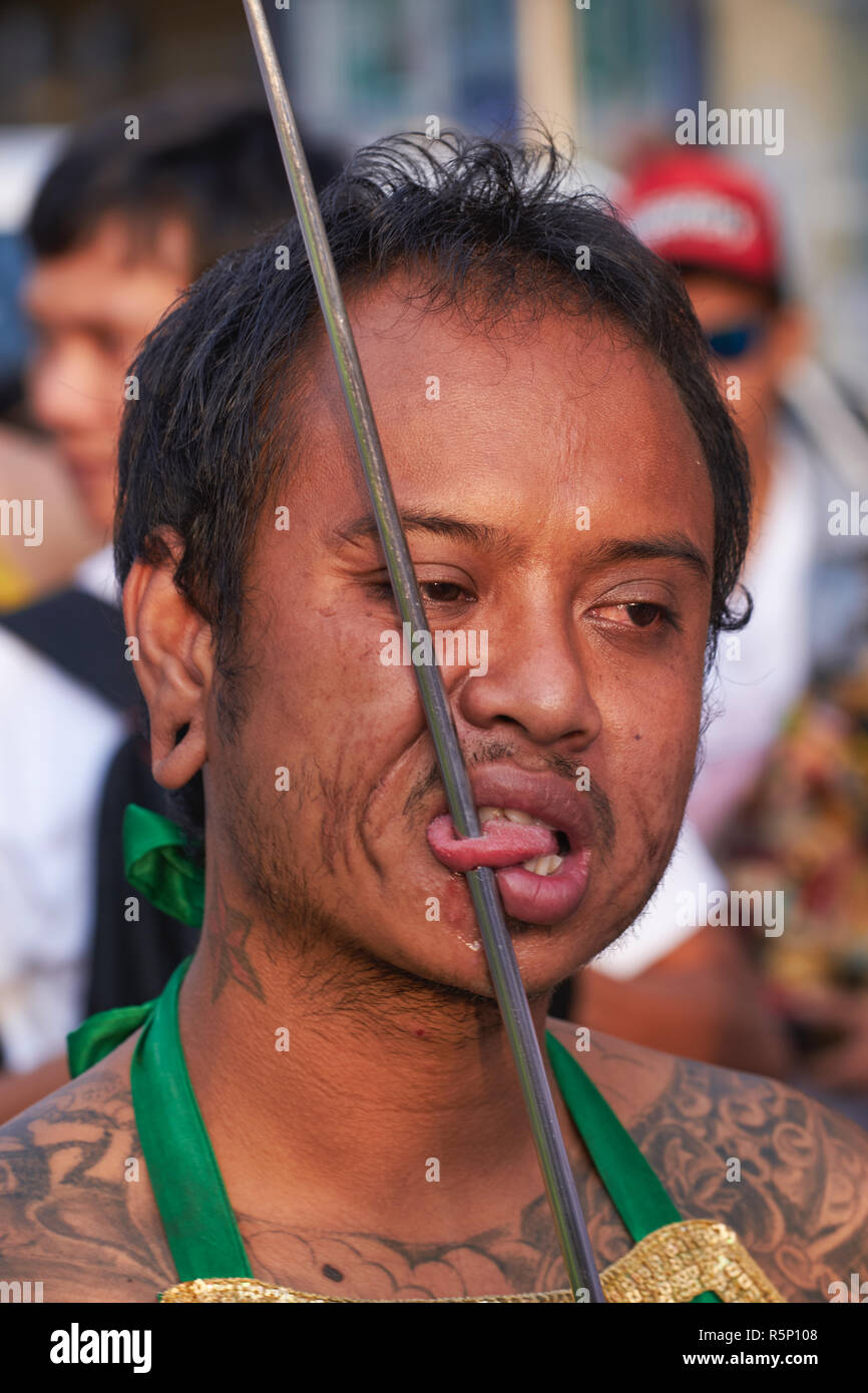 Una processione durante il Festival vegetariano nella città di Phuket, in Thailandia, con un Mah Song o un mezzo spirituale che mostra la sua lingua trafugata da un'asta di ferro Foto Stock