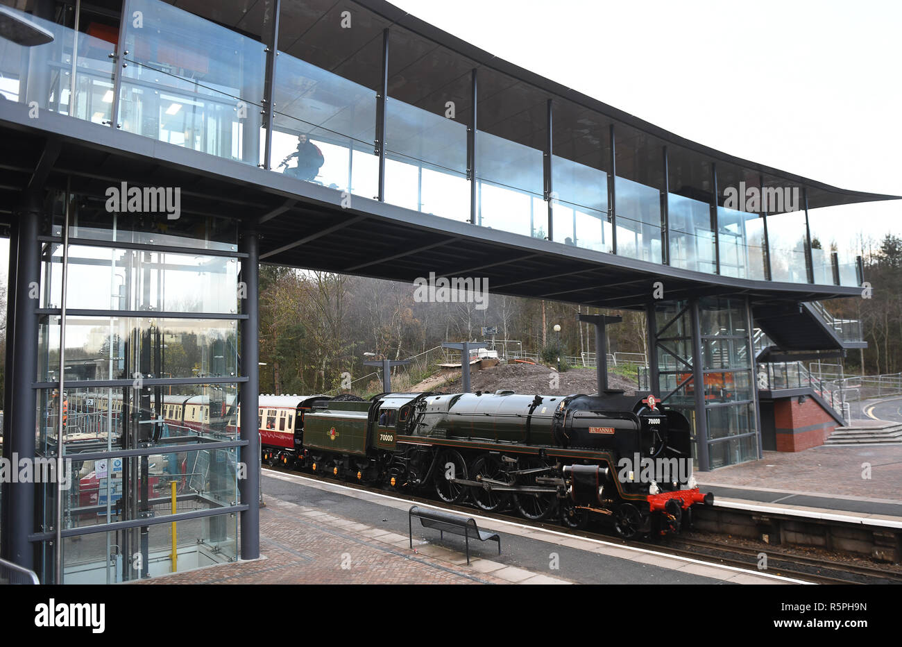 Shropshire, Regno Unito. 2° dic 2018. Il vecchio incontra il nuovo! Britannia locomotiva a vapore arrivando a Telford Central Railway Station sotto il nuovo ponte pedonale che ha aperto questa settimana. La locomotiva fu costruita nel 1952 al costo di £20,325 e il ponte che attraversa la strada adiacente il costo di 10 milioni di sterline. Oggi la locomotiva fu tirando le frontiere gallese Natale Explorer. Credito: David Bagnall/Alamy Live News Foto Stock